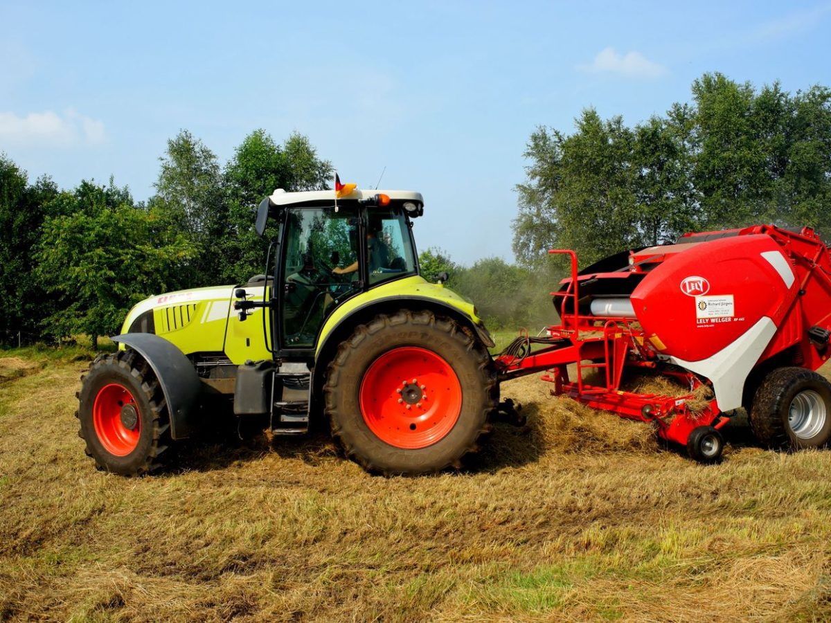Tractor and baler forming round bales from cut crop residue in a stubble field