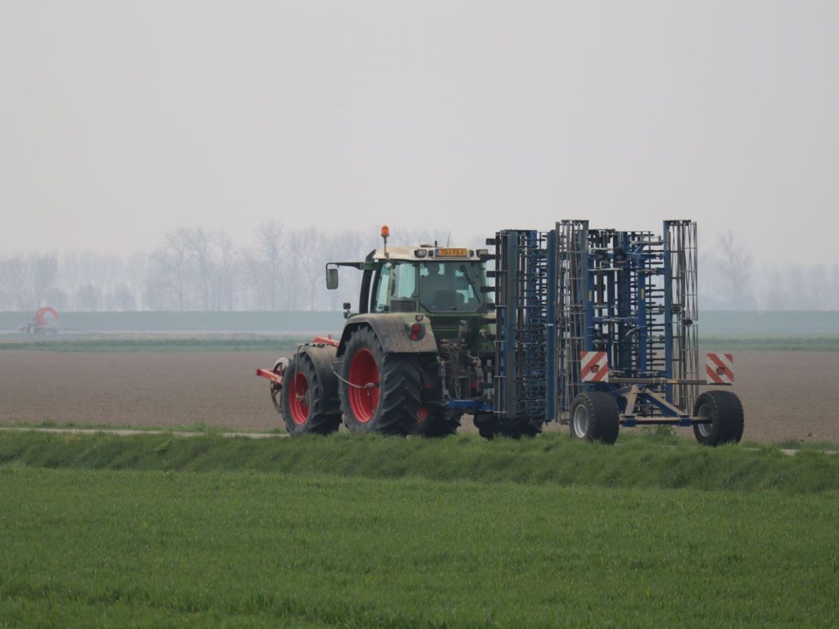 Tractor pulling a cultivator through a field, loosening and levelling the topsoil
